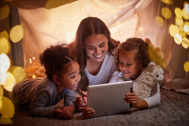 母と子供は、夜にテントでキャンプをするタブレットまたはデジタル子供用アプリで映画をライブストリーミングし、ボケライトをケアしますケアラブママは、幸せな女の子に電子ブックを読んだり、暗闇の中で自宅のwifiでオンラインゲームを読んだりします