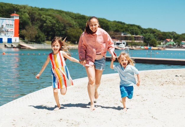 Mother and children run and have fun on the beach at daytime Friendly family concept