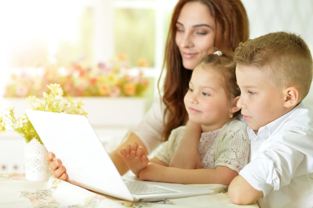 Mother and children sitting at table with laptop