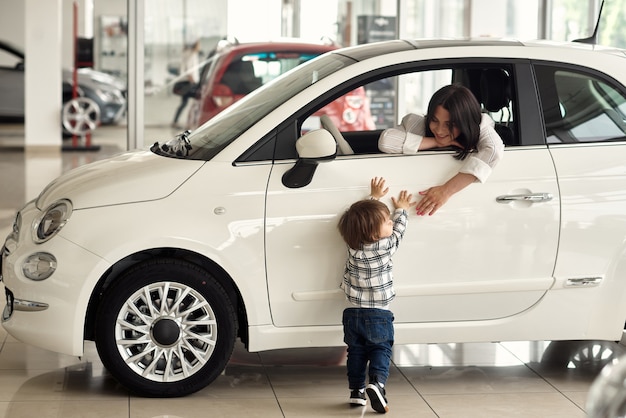 The mother chooses a car in which it will be convenient to carry her little son.