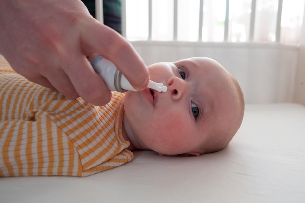 Mother cleaning noe of her baby with nasal drops