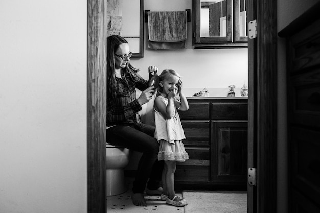 Photo mother combing hair of daughter at home