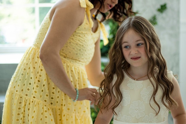 mother combs her daughter before the kids party. A girl in a festive dress with a displeased