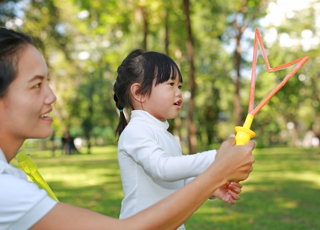 Mother and cute little girl playing bubble in the park.