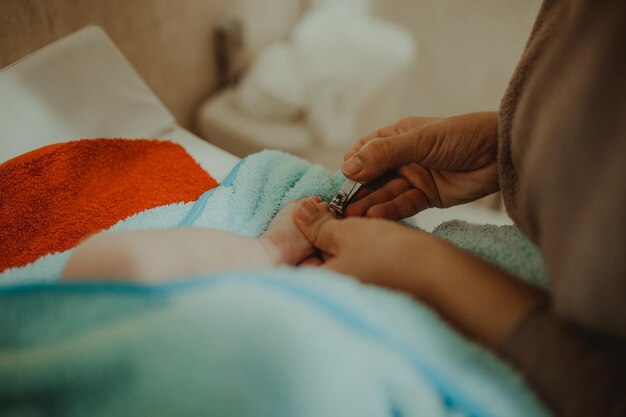 Фото Мама режет ногти ребенку на кровати дома.