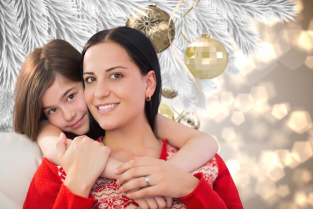 Mother and daughter against christmas decorations on branch