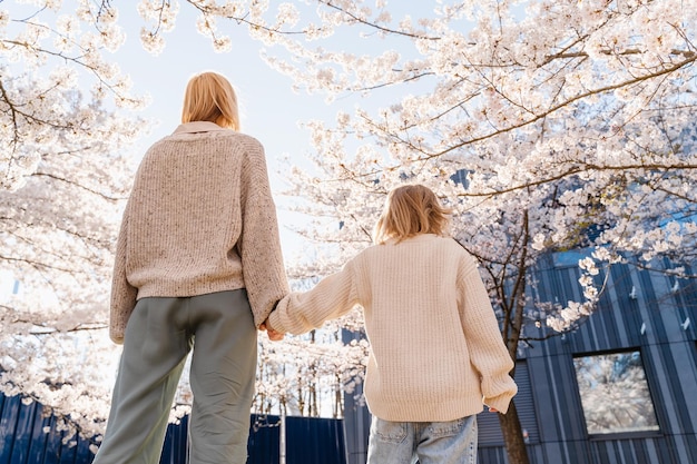 母と娘は家の前にある花の木の庭で一緒に幸せです 母の日おめでとうございます