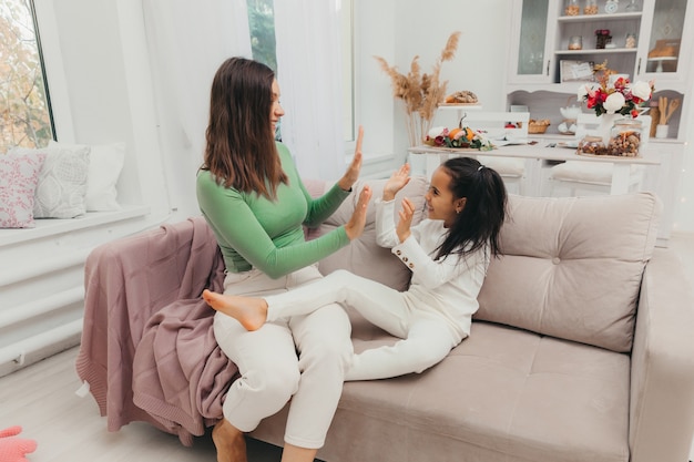 Mother and daughter are having fun in the living room at home\
on the couch. the concept of a tender moment of love and care.\
mothers day.