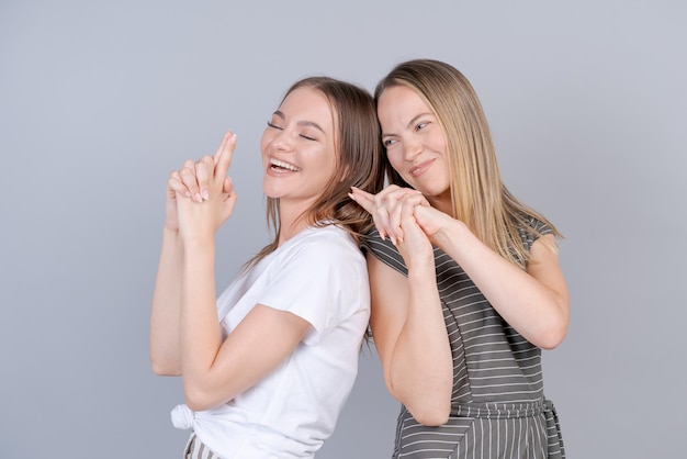 Mother and daughter are hugging and having fun together on background in studio