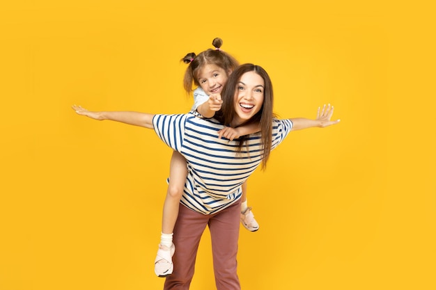 Mother and daughter are playing on a yellow background