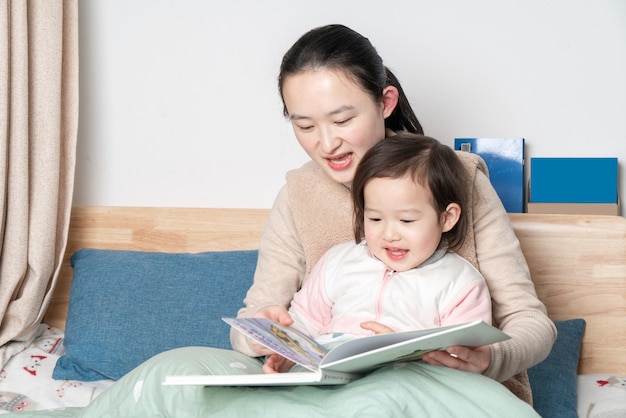 Mother and daughter are reading in bed