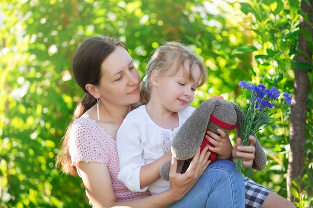 mother and daughter are sitting on a bench in the garden