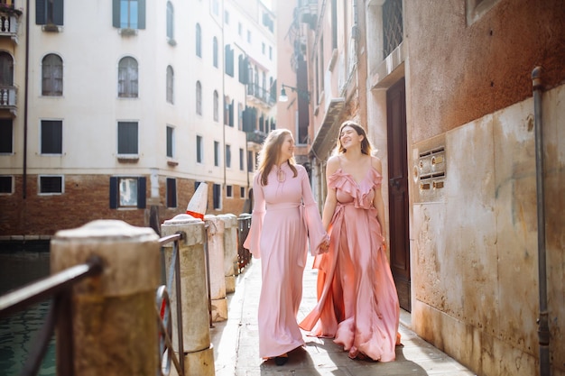 Mother and daughter are walking in sunny Venice in soft pink dresses Concept of active lifestyle