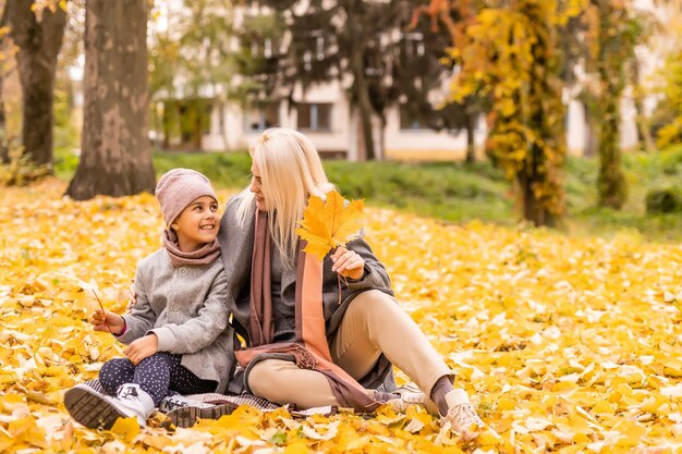 Mother and daughter in autumn yellow park.