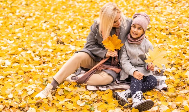 Mother and daughter in autumn yellow park.