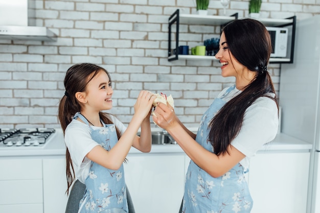 Mother and daughter baking pancakes at kitchen