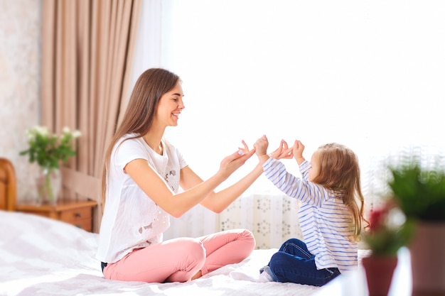 Photo mother and daughter on the bed by the window