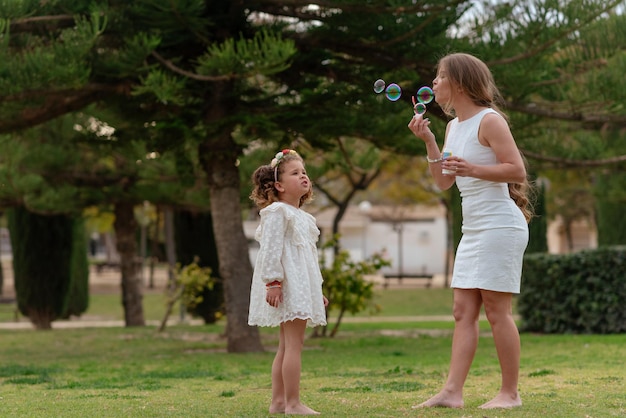 Mother and daughter blow soap bubbles outdoors