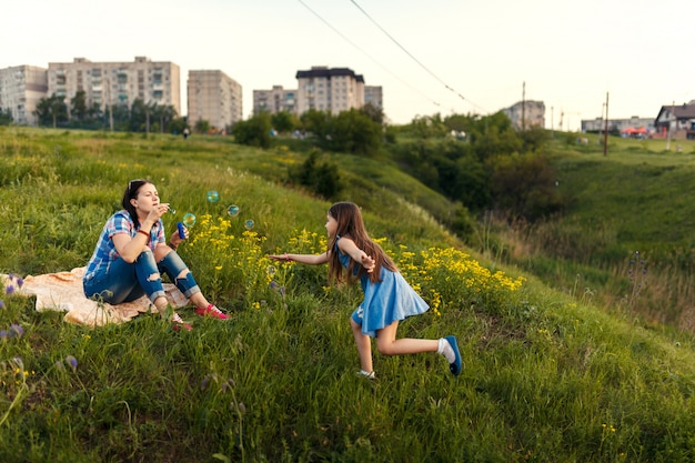 Mother and daughter blowing soap bubbles