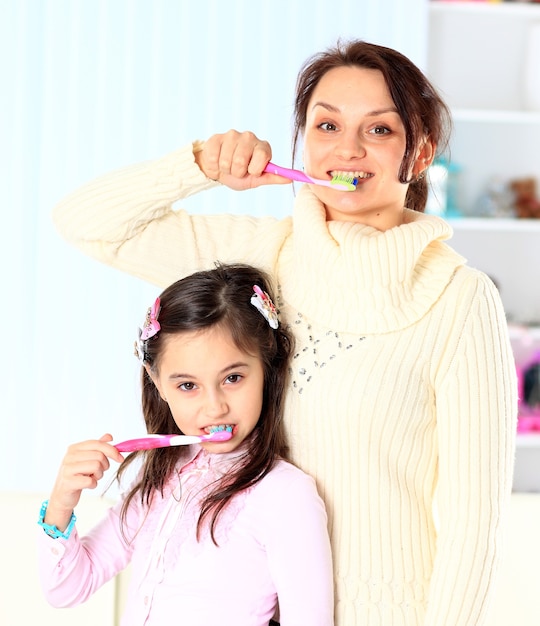 Мать и дочь чистят зубы.