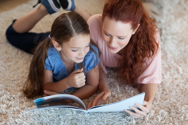 Photo mother and daughter on the carpet reading