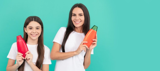 Mother and daughter child banner copy space isolated background smiling mother and daughter hold shampoo bottle on blue background