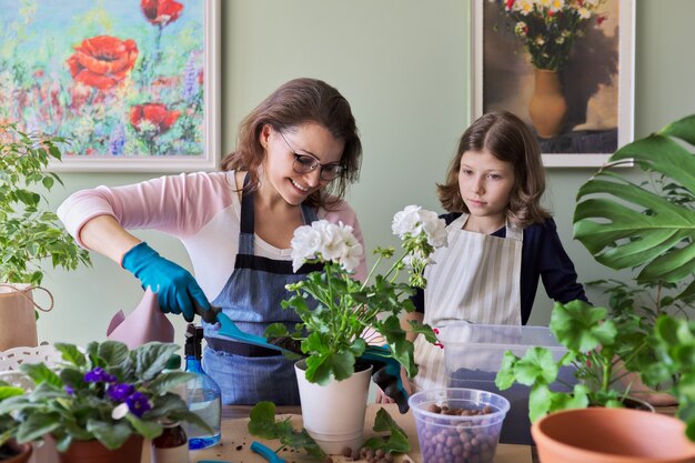 母と娘の子供は鉢植えの植物、花を植えます。趣味とレジャー、ケア、家族、観葉植物、家庭用鉢植えの友達のコンセプト