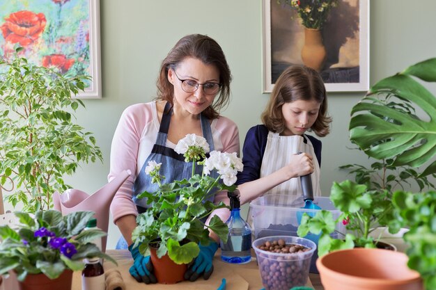 Madre e figlia bambino pianta piante in vaso, fiori. hobby e tempo libero, cura, famiglia, pianta d'appartamento, concetto di amici in vaso di casa