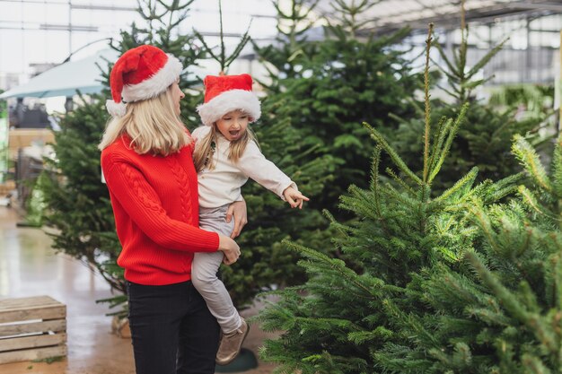 Mother and daughter choose a Christmas tree in a shop