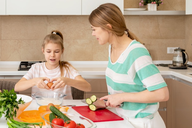 Mother and daughter cook at home. Making cookies, kitchen interior, healthy food concept. Happy, child.