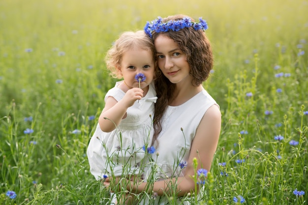 A mother and daughter in a cornflower field enjoy the fragrance of flowers.