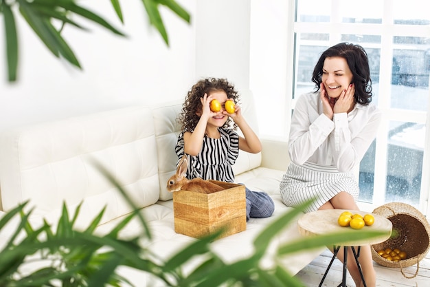 Mother and daughter cute beautiful and happy with rabbits and Easter eggs at home together