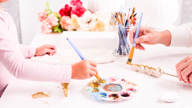 Mother and daughter decorating craft pumpkins with unicorn theme for Halloween.