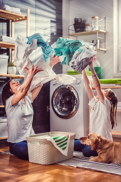 Mother, daughter and dog having fun at laundry room