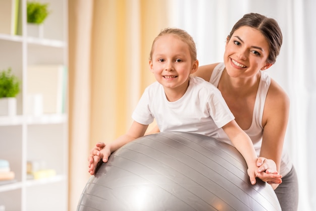 Мать и дочь делают физические упражнения на фитнес-мяч
