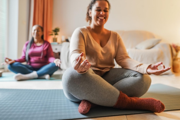 Photo mother and daughter doing yoga exercises at home together family and sport concept during winter time focus on girl left hand