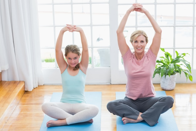 Madre e figlia che fanno yoga sul tappetino fitness