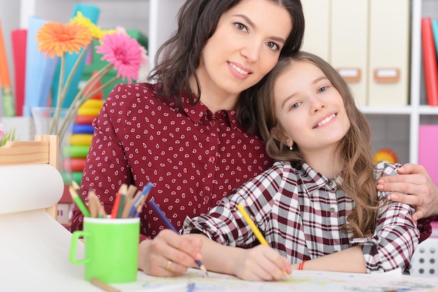 Mother and daughter drawing together in room