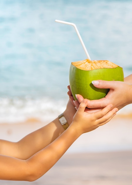 Мать и дочь пьют кокос на пляже