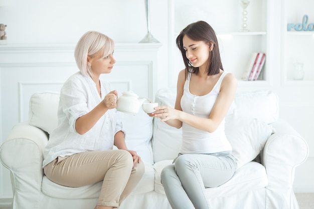 Мать и дочь пьют чай в помещении