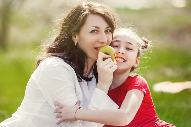 Mother and daughter eating an apple in nature