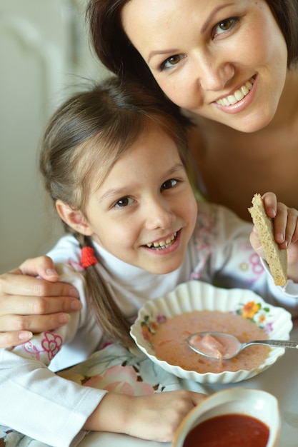 家のテーブルでスープを食べる母と娘