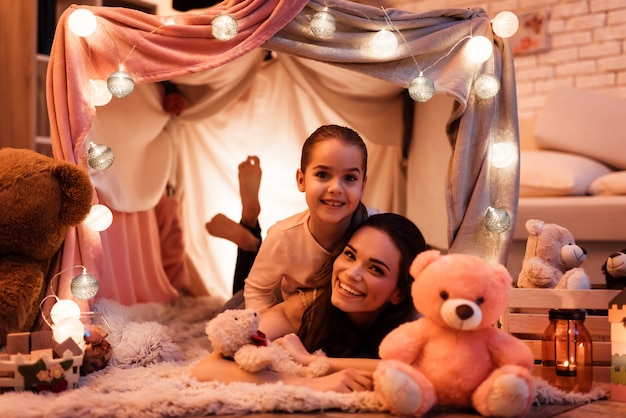 Mother and daughter embracing each other in pillow house.