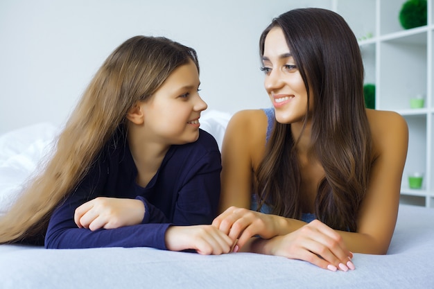 Mother and daughter enjoy in bed at home