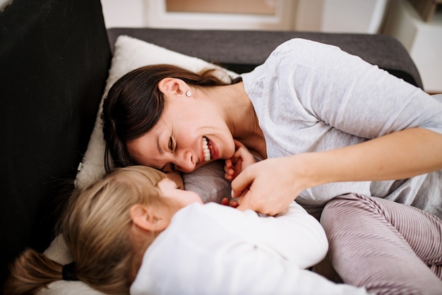 Mother and daughter enjoy lying in bed at home. Top view.