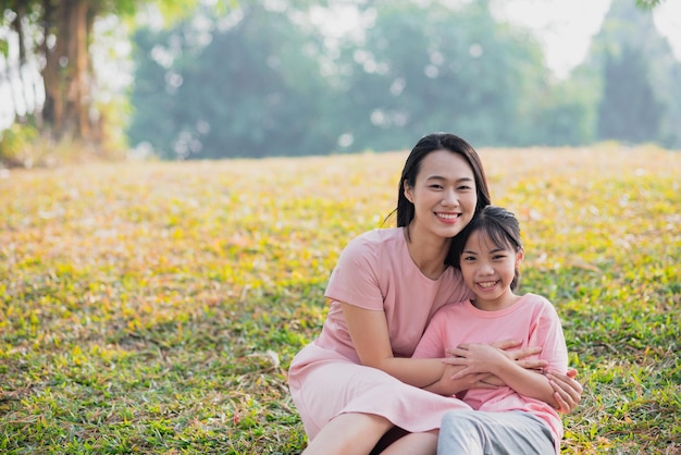 Mother and daughter enjoying a sunny afternoon in a park smiling and playing together