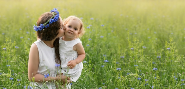 Mother and daughter in a field of cornflowers at sunset