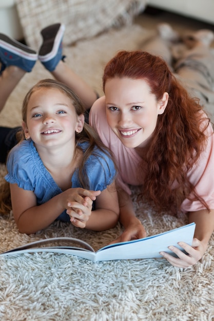 Photo mother and daughter on the floor reading