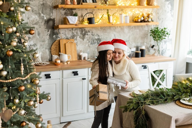 Mother and daughter in front of Christmas tree.