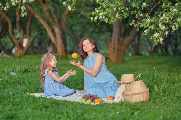 Mother and daughter in the garden, eating fruit.